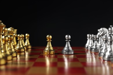 Photo of Golden and silver pawns near other chess pieces on chessboard against black background, closeup. Competition concept