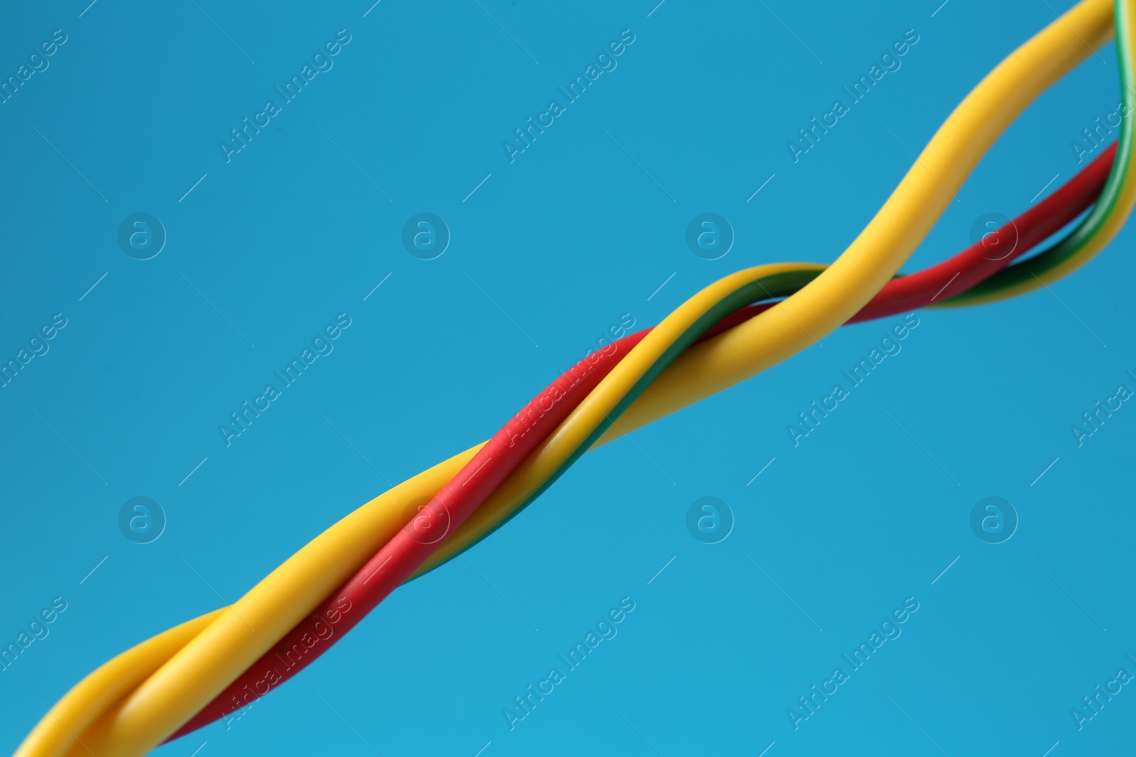 Photo of Many color electrical wires on light blue background, closeup