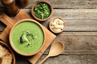 Photo of Delicious broccoli cream soup served on wooden table, flat lay. Space for text