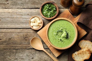 Photo of Delicious broccoli cream soup served on wooden table, flat lay. Space for text