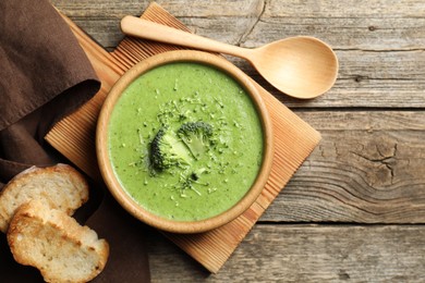 Photo of Delicious broccoli cream soup served on wooden table, flat lay