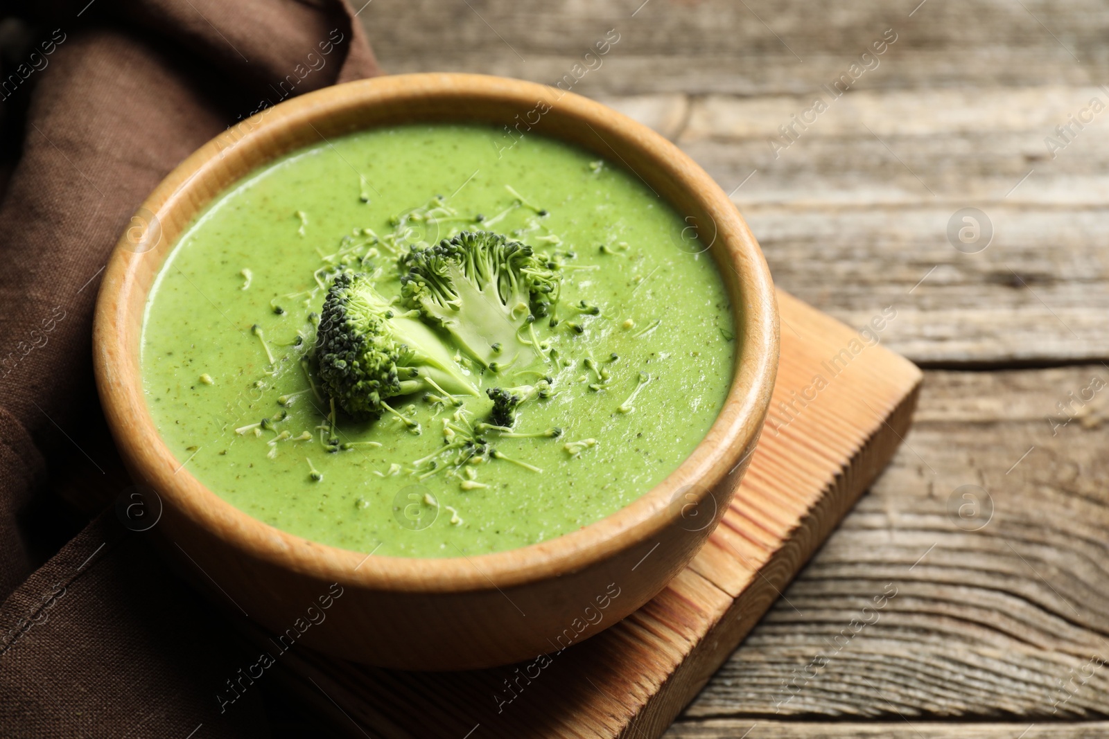 Photo of Delicious broccoli cream soup in bowl on wooden table, closeup