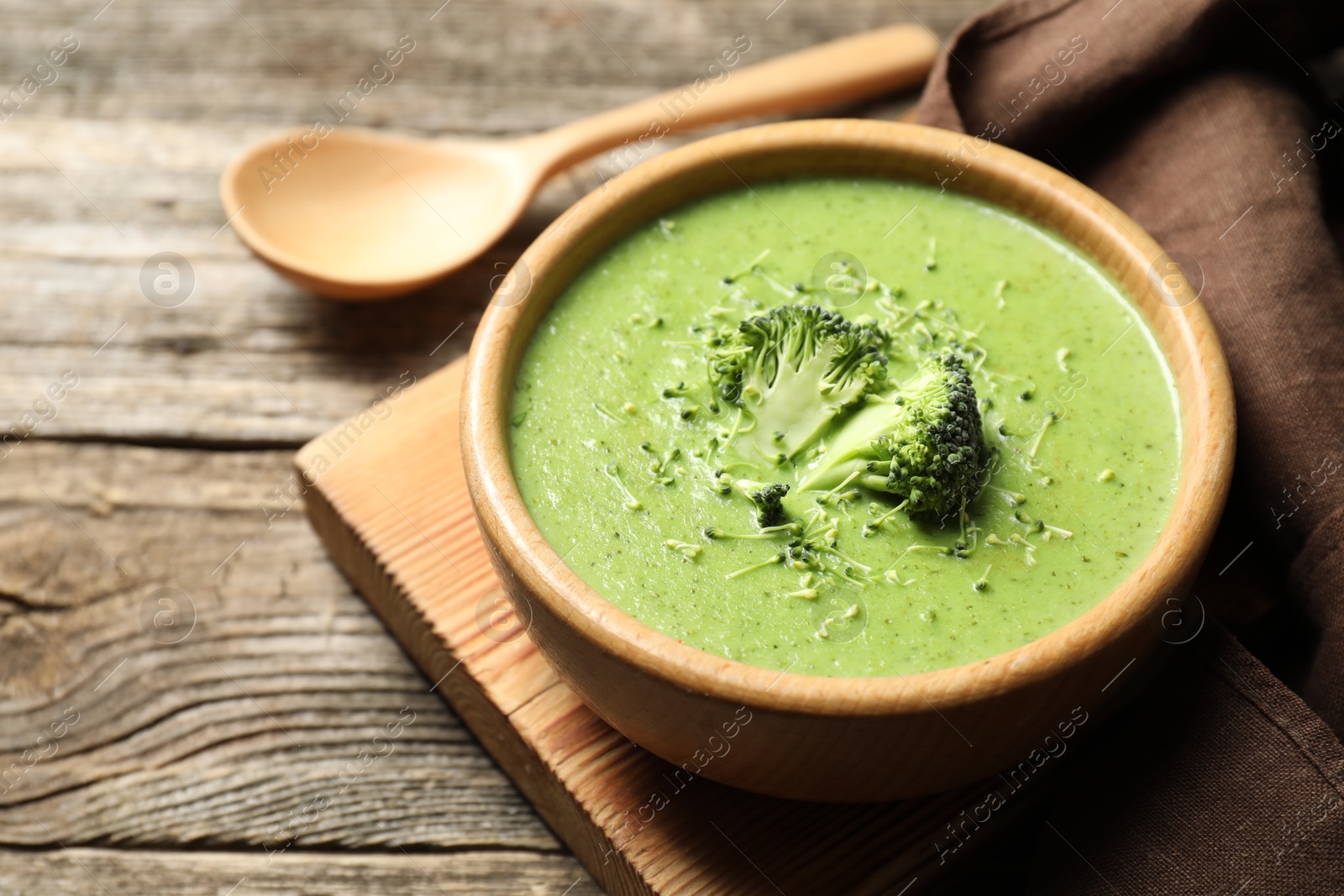 Photo of Delicious broccoli cream soup served on wooden table, closeup