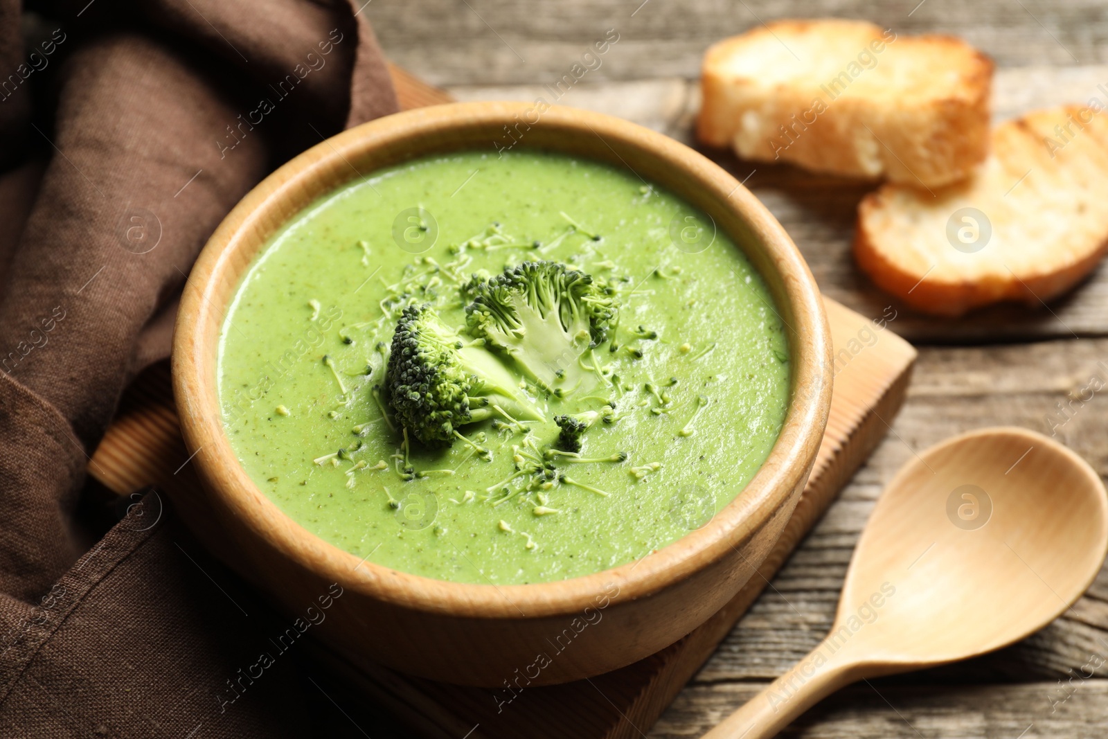 Photo of Delicious broccoli cream soup served on wooden table, closeup