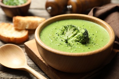 Photo of Delicious broccoli cream soup served on wooden table, closeup