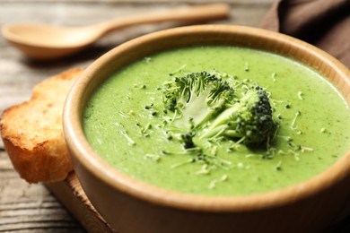 Photo of Delicious broccoli cream soup served on wooden table, closeup