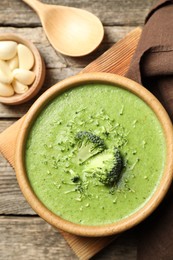 Photo of Delicious broccoli cream soup served on wooden table, flat lay