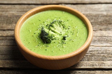 Photo of Delicious broccoli cream soup in bowl on wooden table, closeup