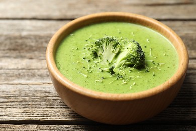 Photo of Delicious broccoli cream soup in bowl on wooden table, closeup