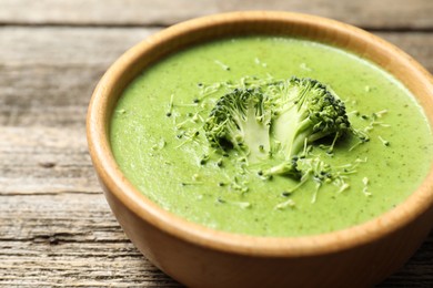 Photo of Delicious broccoli cream soup in bowl on wooden table, closeup