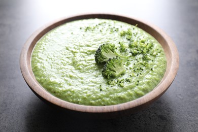 Photo of Delicious broccoli cream soup in bowl on grey table, closeup