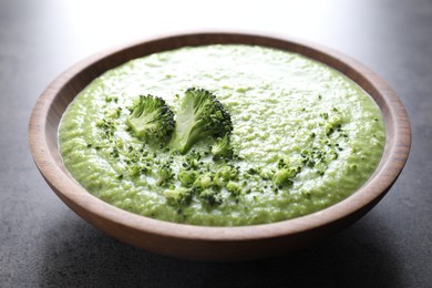 Photo of Delicious broccoli cream soup in bowl on grey table, closeup