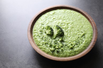 Photo of Delicious broccoli cream soup in bowl on grey table, closeup