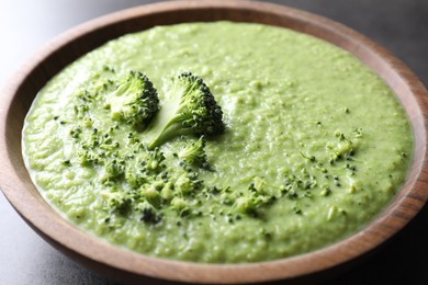 Photo of Delicious broccoli cream soup in bowl on grey table, closeup