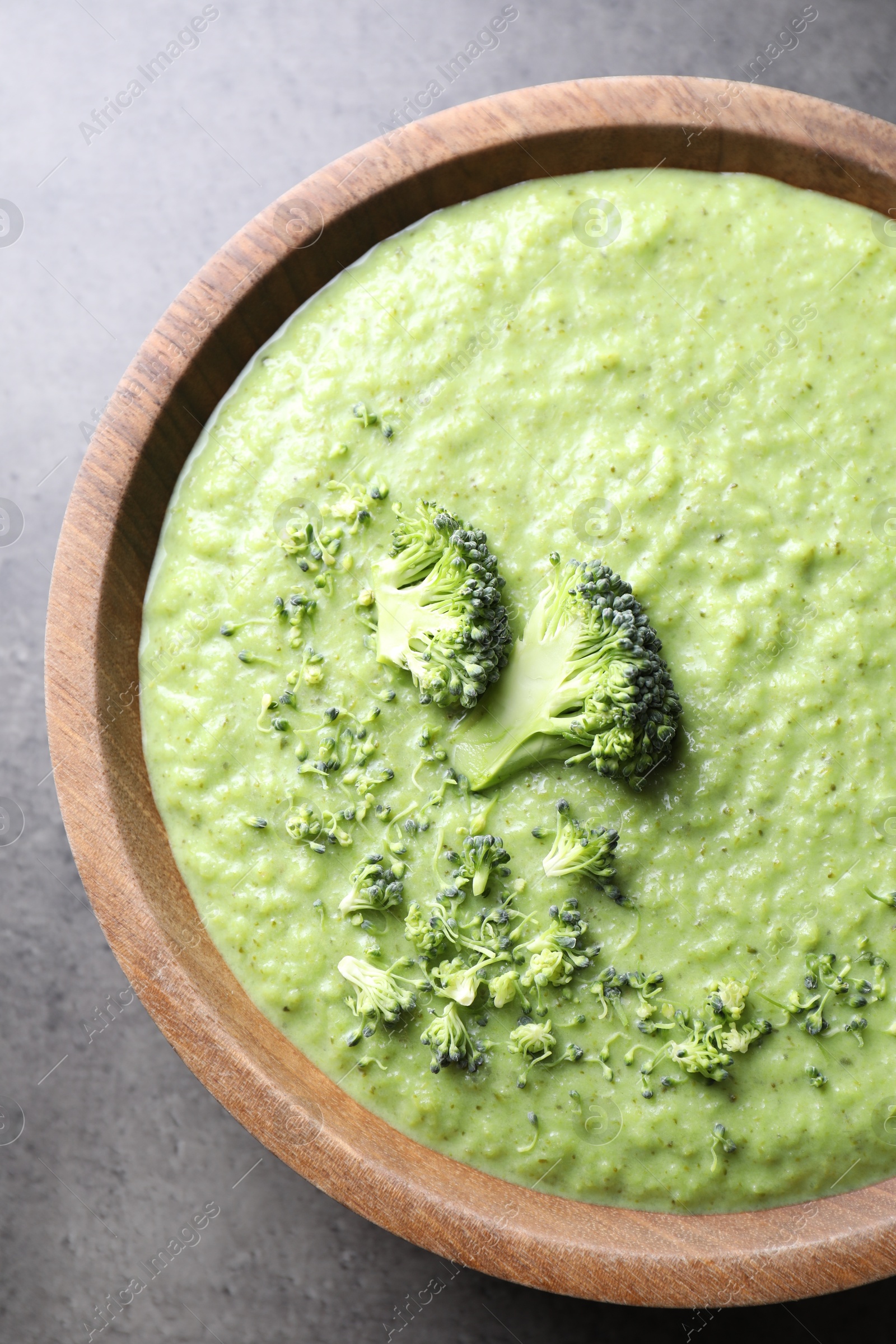 Photo of Delicious broccoli cream soup in bowl on grey table, top view