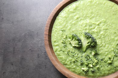 Photo of Delicious broccoli cream soup in bowl on grey table, top view. Space for text