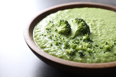 Photo of Delicious broccoli cream soup in bowl on grey table, closeup