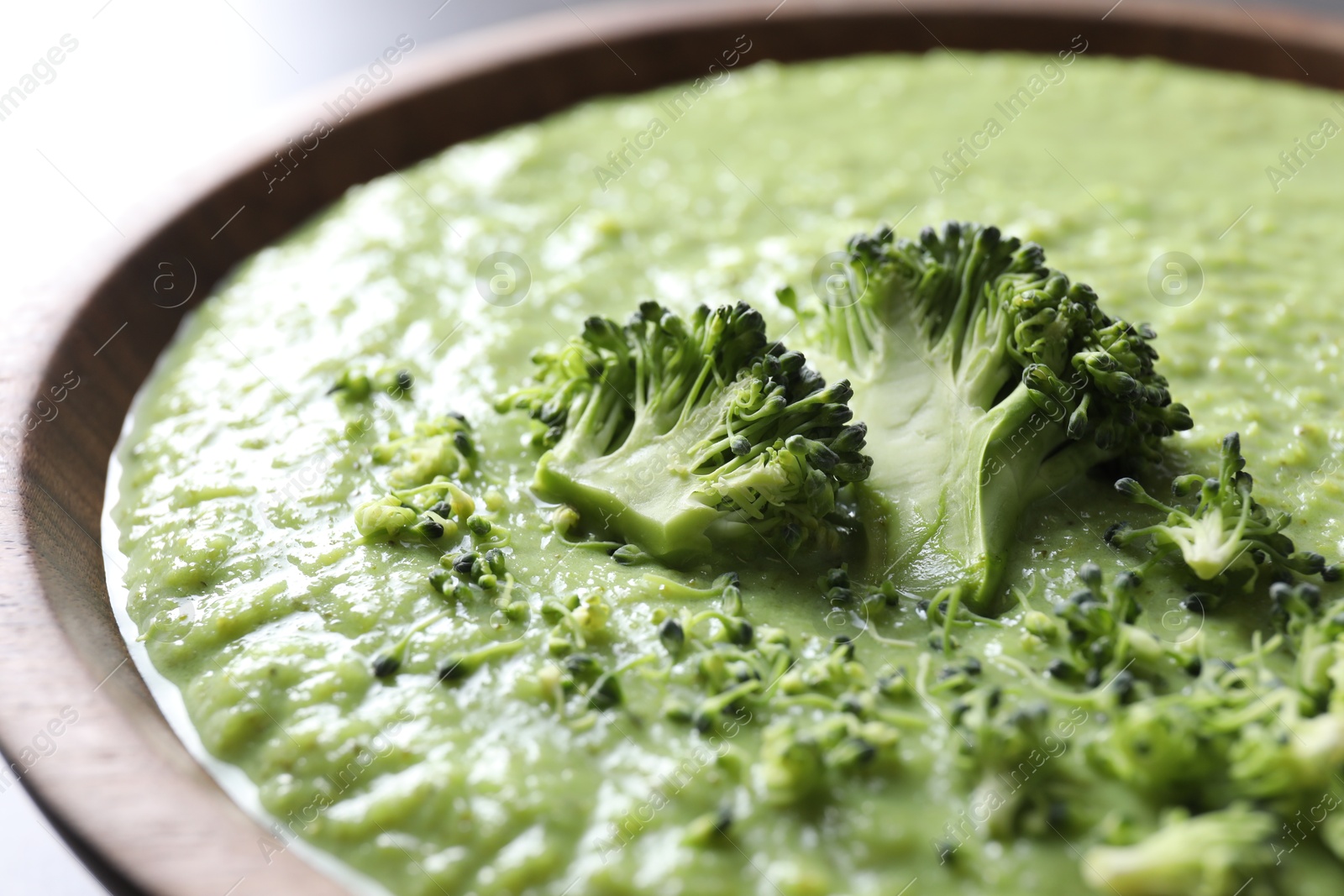 Photo of Delicious broccoli cream soup in bowl on table, closeup