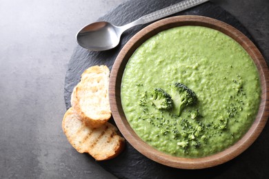 Photo of Delicious broccoli cream soup served on grey table, flat lay