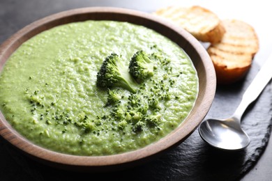 Photo of Delicious broccoli cream soup served on grey table, closeup