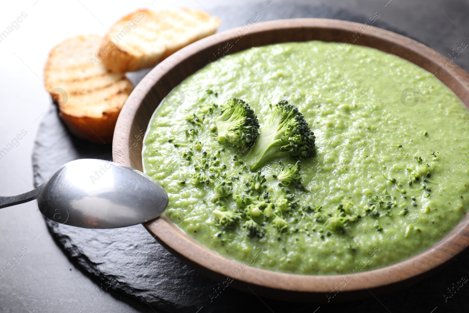 Photo of Delicious broccoli cream soup served on grey table, closeup