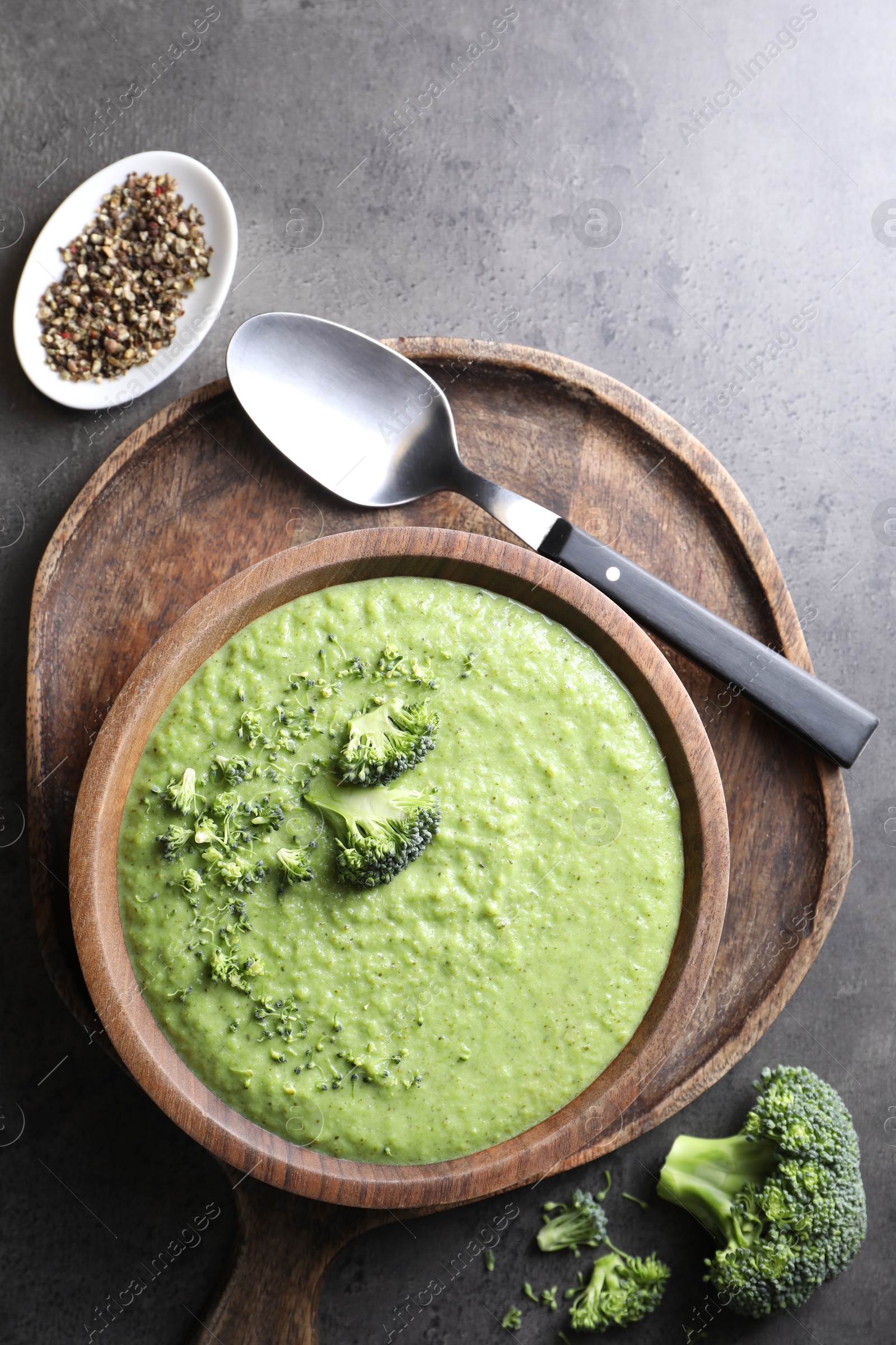 Photo of Delicious broccoli cream soup served on grey table, flat lay