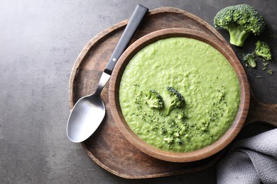 Photo of Delicious broccoli cream soup served on grey table, flat lay