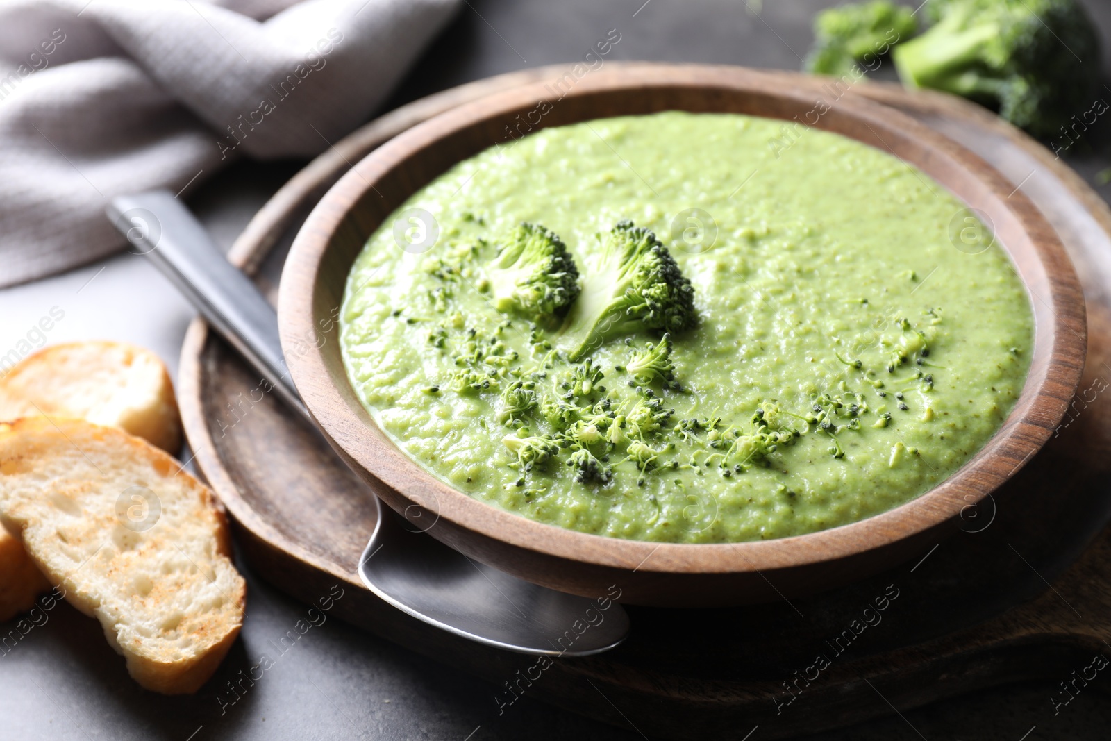 Photo of Delicious broccoli cream soup served on grey table, closeup