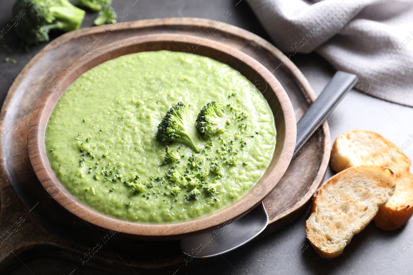 Photo of Delicious broccoli cream soup served on grey table, closeup