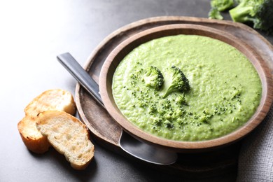 Photo of Delicious broccoli cream soup served on grey table, closeup