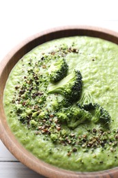 Photo of Delicious broccoli cream soup in bowl on white table, closeup