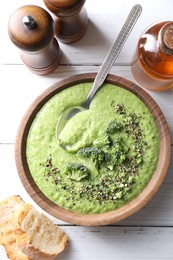 Photo of Delicious broccoli cream soup served on white wooden table, flat lay