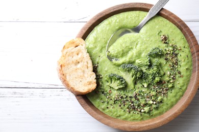 Photo of Delicious broccoli cream soup served on white wooden table, top view. Space for text