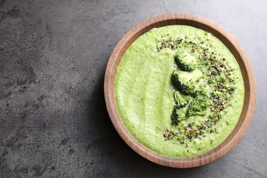 Photo of Delicious broccoli cream soup in bowl on grey table, top view. Space for text