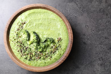 Photo of Delicious broccoli cream soup in bowl on grey table, top view. Space for text