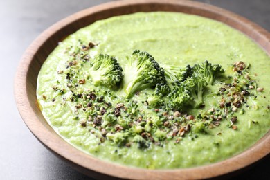 Photo of Delicious broccoli cream soup in bowl on grey table, closeup