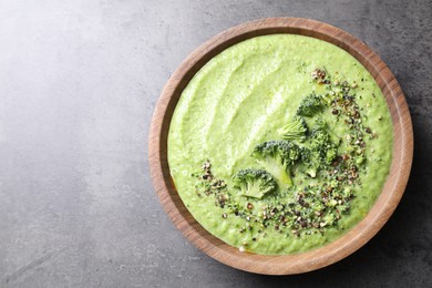 Photo of Delicious broccoli cream soup in bowl on grey table, top view. Space for text