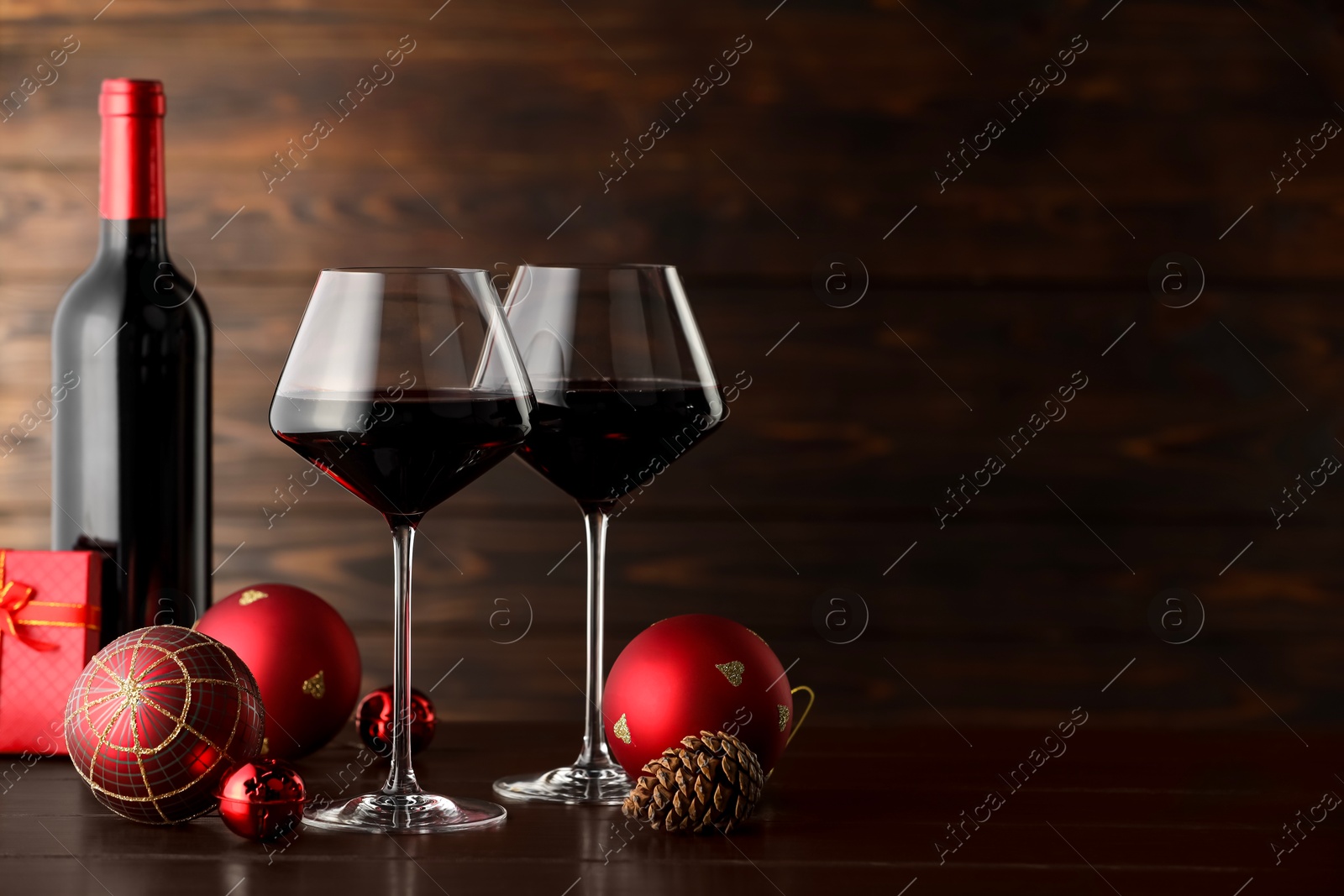 Photo of Red wine and beautiful Christmas decor on wooden table. Space for text