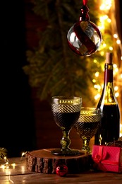 Photo of Red wine and beautiful Christmas decor on wooden table against blurred festive lights. Space for text