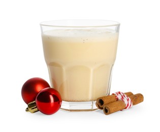 Photo of Tasty Christmas cocktail (eggnog) in glass, cinnamon and baubles isolated on white