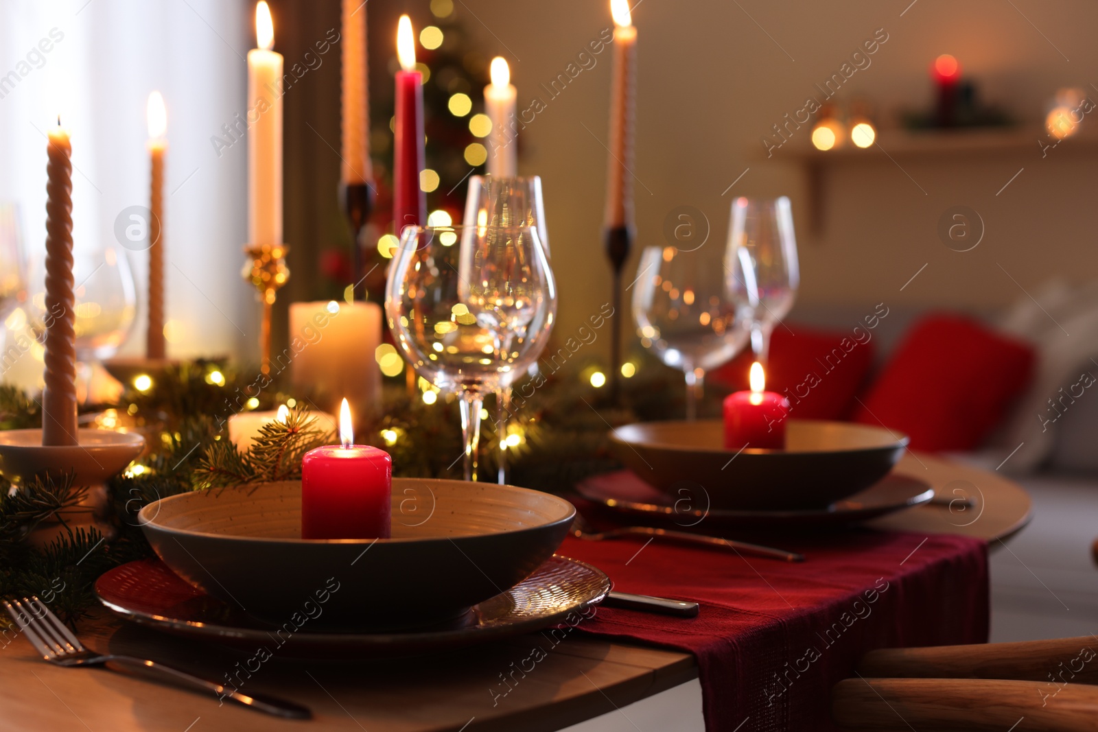 Photo of Festive table setting in room decorated for Christmas, closeup. Bokeh effect