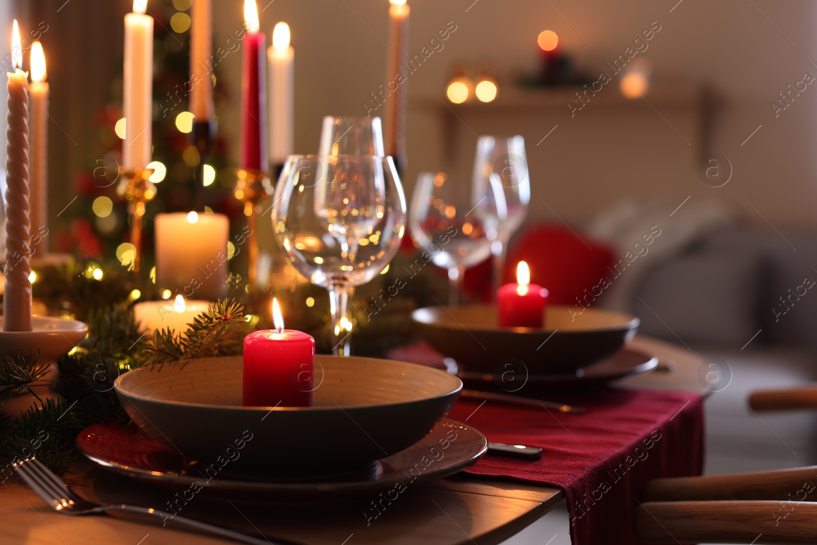 Photo of Festive table setting in room decorated for Christmas, closeup. Bokeh effect