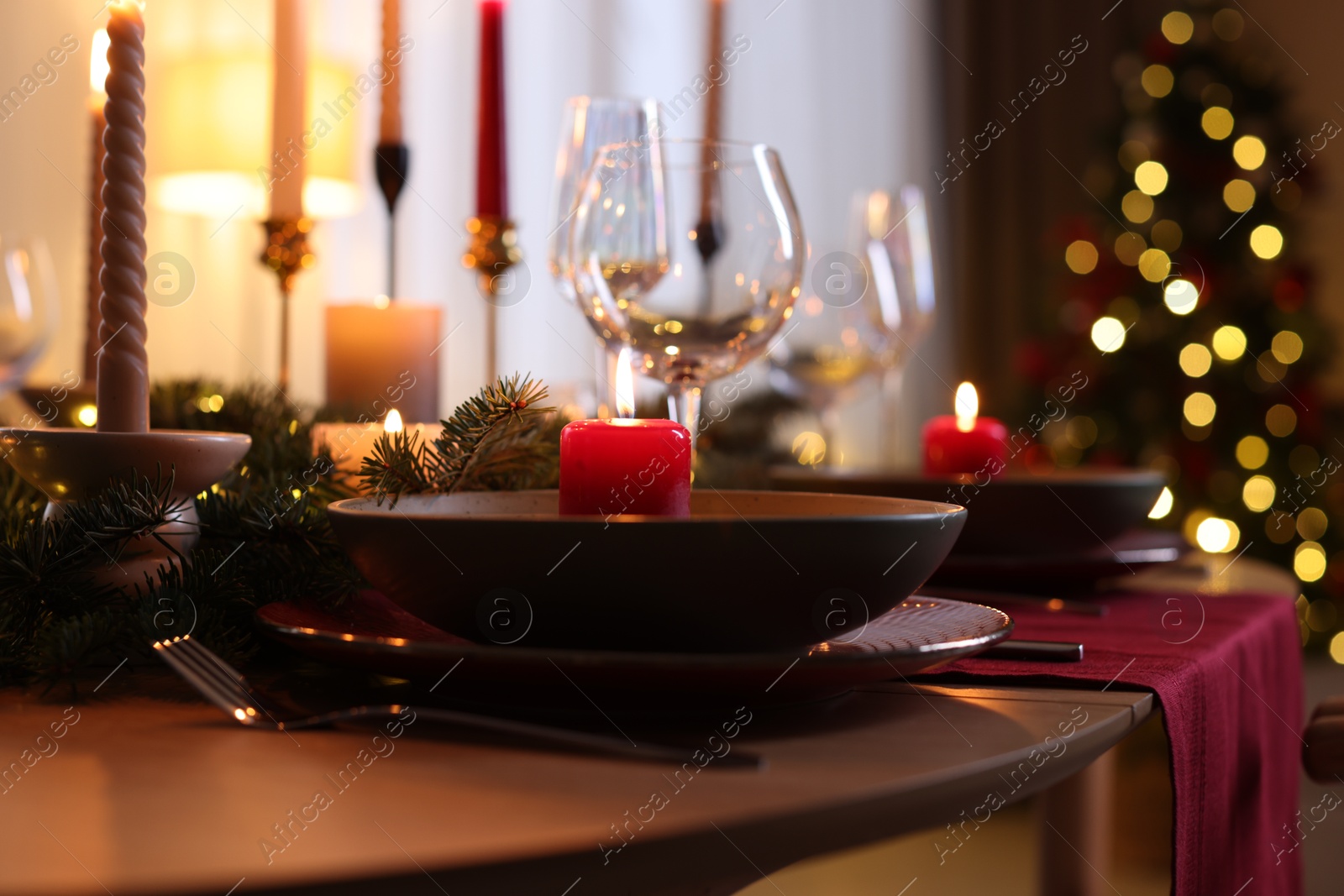 Photo of Festive table setting in room decorated for Christmas, closeup. Bokeh effect