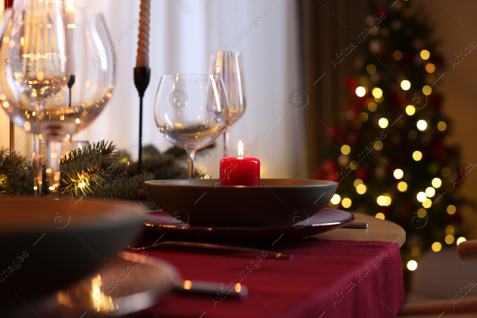 Photo of Festive table setting in room decorated for Christmas, closeup. Bokeh effect