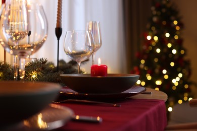 Photo of Festive table setting in room decorated for Christmas, closeup. Bokeh effect