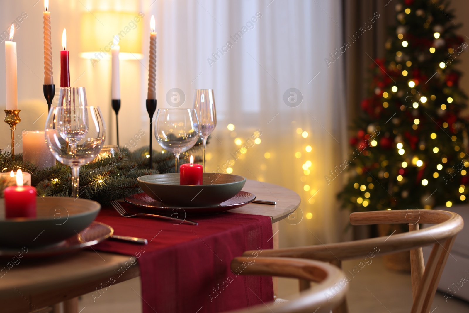 Photo of Festive table setting in room decorated for Christmas, closeup. Bokeh effect