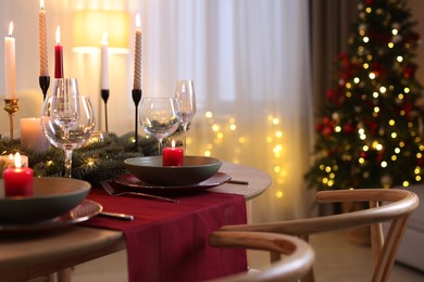 Photo of Festive table setting in room decorated for Christmas, closeup. Bokeh effect