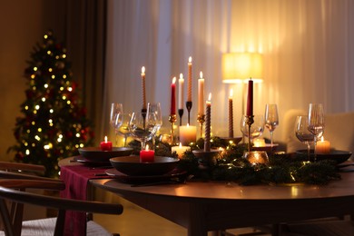 Photo of Festive table setting in room decorated for Christmas. Bokeh effect