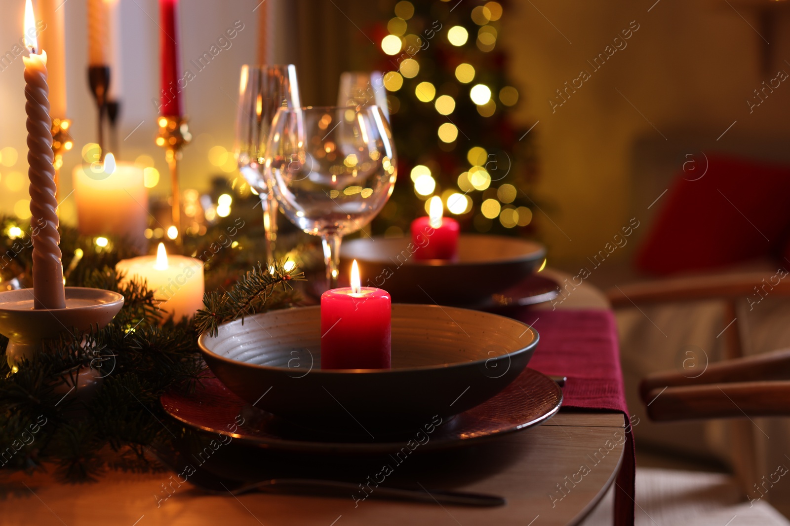 Photo of Festive table setting in room decorated for Christmas, closeup. Bokeh effect