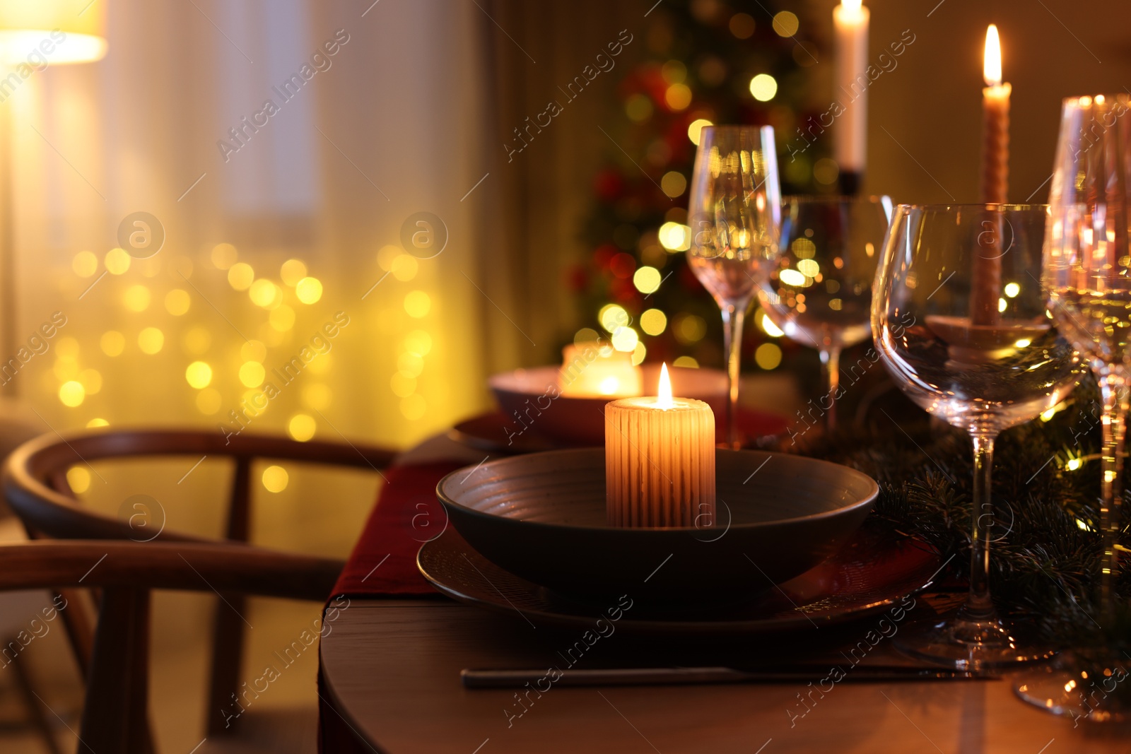 Photo of Festive table setting in room decorated for Christmas, closeup. Bokeh effect